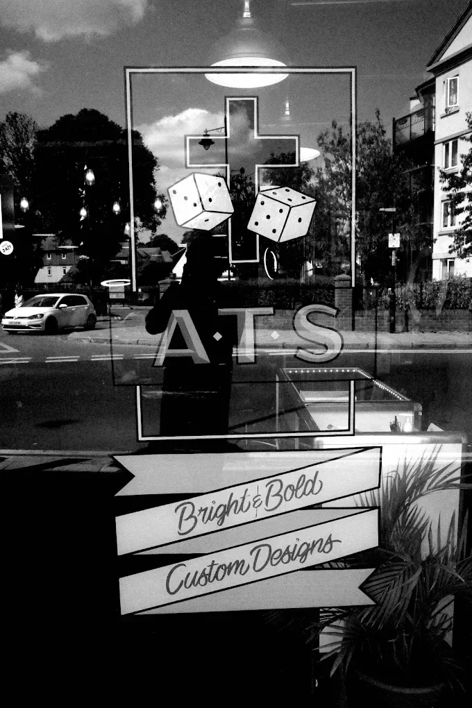 Avinit Tattoo Studio artwork with the cross and dice emblem